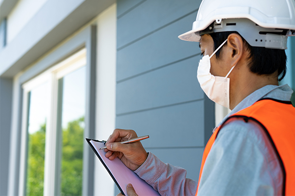 Image: Engineer or an adjuster reviewing a home with a clipboard