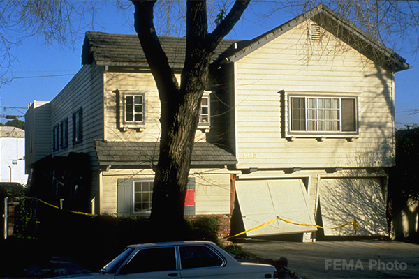 Image: Damaged front of house from the 1996 Northridge Earthquake that shows damaged from a living space over a garage or soft story.