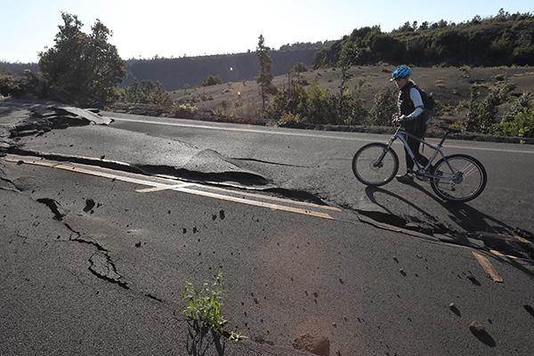 Image: Man with bicycle looking at cracked road