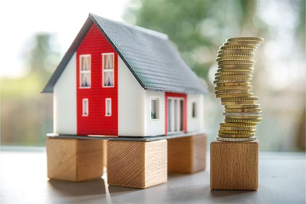 Image: Wooden house on blocks next to gold coins